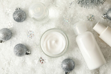 Concept of face care with cosmetics on background with decorative snow