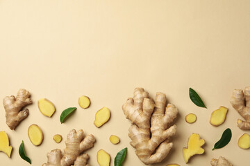 Fresh ginger and leaves on beige background, top view