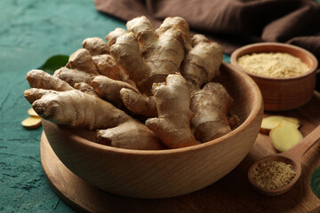 Board with fresh ginger on green background