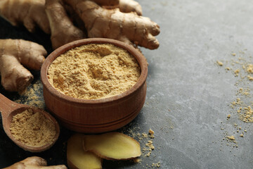 Ginger and bowl with ginger powder on black smoky background