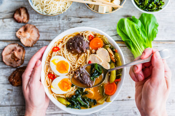 Woman's hands and traditional ramen soup.
