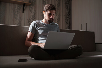 Remote Job. Man Working On Laptop Sitting On Sofa At Home.