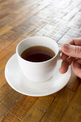 Hand holding a white cup of tea