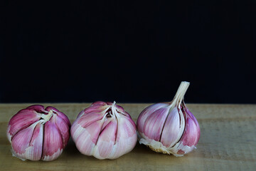 Fresh garlic on a wooden cut board and black background.