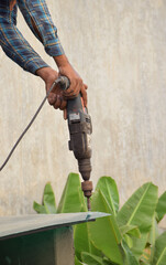 An Indian worker using his drilling machine to tighten the bolts in a plastic sheet