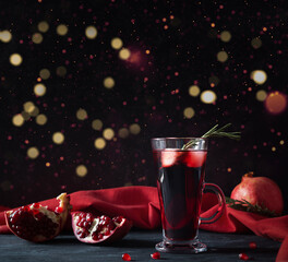 Pomegranate Christmas cocktail with champagne, club soda and rosemary on black table.