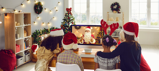 Chatting a group of children online with Santa using a computer webcam at home at Christmas