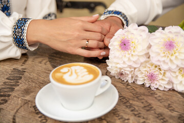 Obraz na płótnie Canvas Wedding rings on the hands of brides. Fragrant, hot cappuccino on the table.