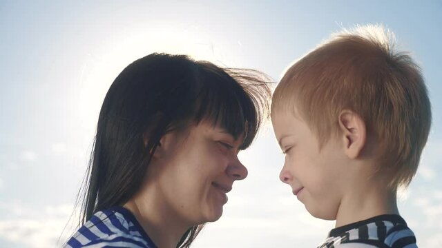 son and mom cute video concert mother's day. teamwork happy family boy kisses mother on the cheek touches his nose lifestyle . parent takes care of the child. kid and adult woman mom in the sunlight