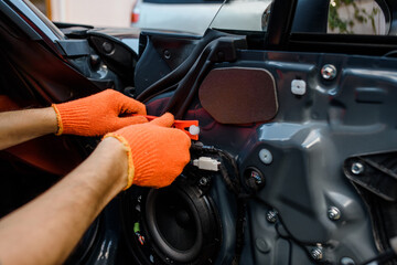 Close up repairman hands repair the interior of a car door.