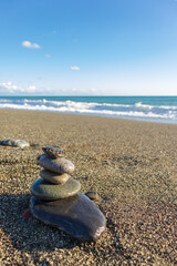 Pyramid of the stones on a sandy beach against the sea