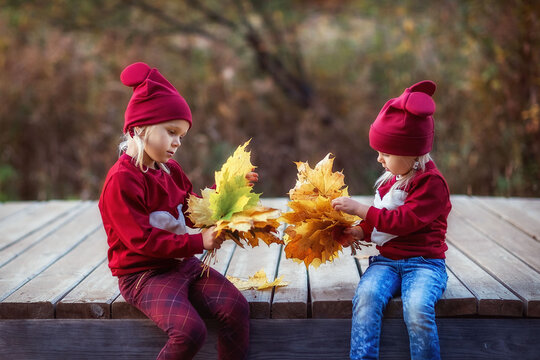 Little Sister Girls Walking In Autumn By The Lake In The Park, Playing With Leaves, Hugging, Love, Family, Matching Clothes For Children