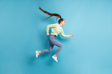 Full length body size side profile photo of jumping running hurrying girl with long hair ponytail isolated on bright blue color background