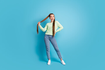 Photo portrait of girl showing tongue holding hair isolated on pastel blue colored background © deagreez