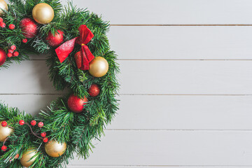 Christmas wreath with decorations on a white wooden backgroung with snow and space for message