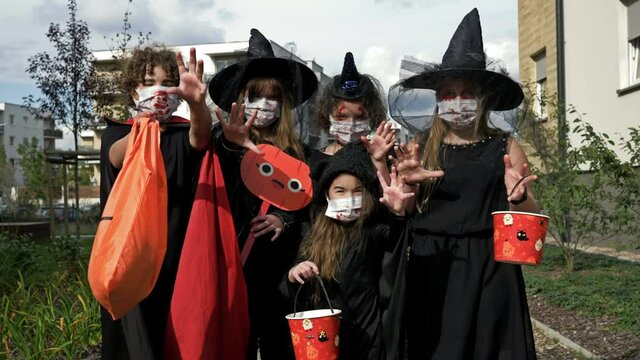Group portrait of children in black fancy dress. Everyone has medical masks on their faces. Halloween during the covid19 coronavirus pandemic.