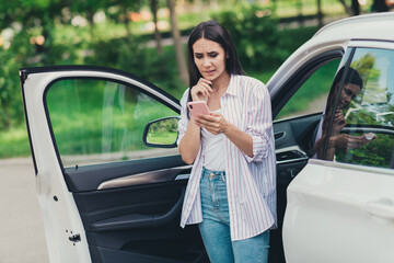 Photo of unsure minded girl driver ride car road lost check smartphone gps navigation hesitate bite...
