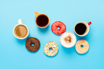 Tasty donuts and cups with hot drinks, coffee, cappuccino, tea on a blue background. Concept of...