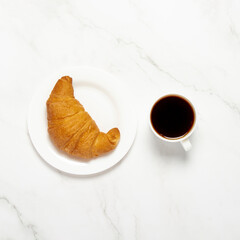 Cup with black coffee and croissant on a marble background. Concept bakery, pastries, french breakfast. Flat lay, top view