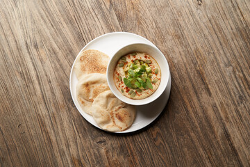 Hummus with avocado and herbs in white bowl