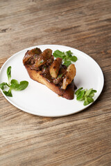 Toast with baked chicken liver on white plate on table
