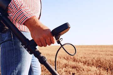 Man with metal detector equipment searching for metal goods in the field