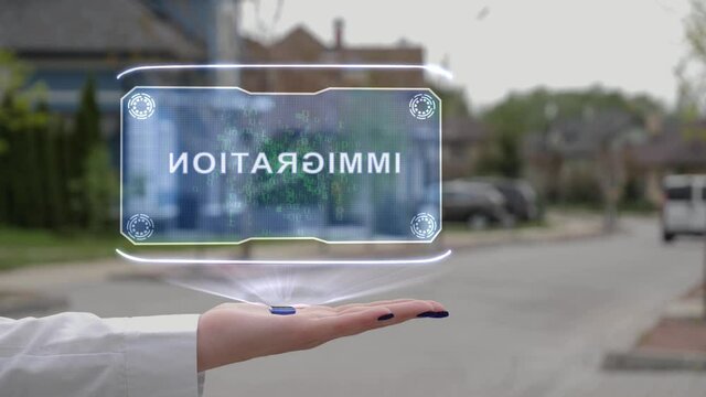 Female hand showing conceptual hologram with Immigration text. Unrecognizable woman in white holds future holographic technology on the background of a street with private houses