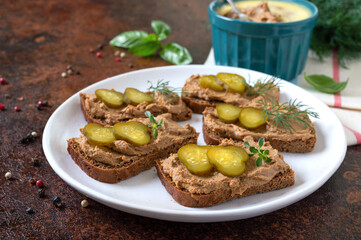 Canapes with chicken liver pate and pickled cucumbers on rye bread. Tasty and healthy appetizer.
