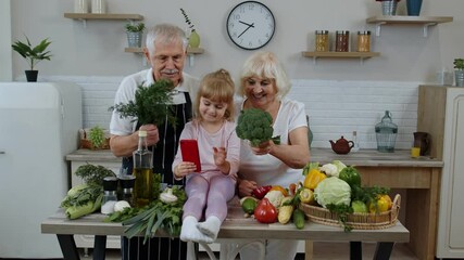 Blogger girl making selfie on phone with senior couple grandparents at kitchen with vegetables - Powered by Adobe