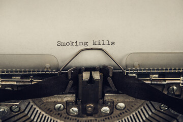 typing a warning slogan smoking kills on a vintage typewriter close-up. old and grunge atmosphere