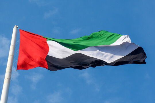 United  Arab Emirates Flag flying and waving in the sunshine with a deep blue sky background.