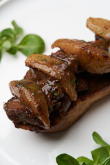 Toast with baked chicken liver on white plate on table