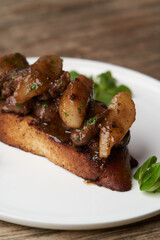 Toast with baked chicken liver on white plate on table