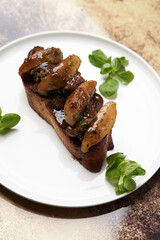 Toast with baked chicken liver on white plate on table