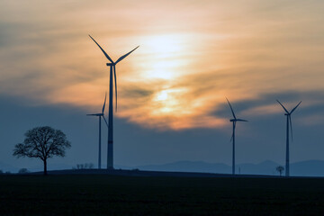 windräder auf einem feld am abend, windenergie