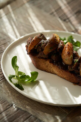 Toast with baked chicken liver on white plate on table