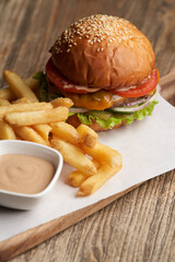 Fresh burger and french fries on wooden cutting board