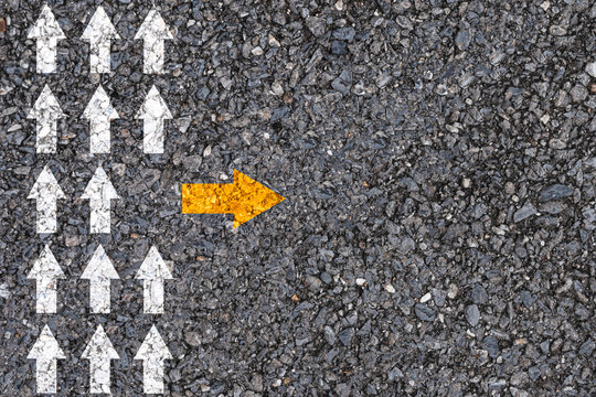 Different thinking and Business and technology disruption concept. Yellow arrow out of line  direction with white arrow on road asphalt.