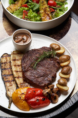 Ribeye steak with fried potatoes. Baked vegetables with beef steak on white plate