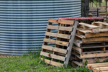 Stack of wooden pallets next to corrugated iron tank on country property