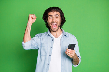 Portrait of his he nice attractive cheerful cheery glad guy using device celebrating great luck sale rejoicing isolated over bright vivid shine vibrant green color background