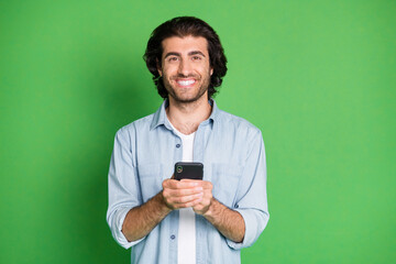 Portrait of his he nice attractive cheerful cheery glad mature guy using gadget device app 5g chatting isolated over bright vivid shine vibrant green color background