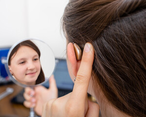 Advertising hearing aid for children, a caucasian race child showing a hearing aid behind the ear. Children's hearing treatment