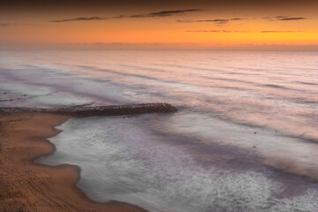 Stone jetty in the middle of the beach after sunset, Ericeira Portugal