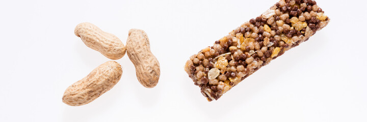 Healthy granola bar (muesli or cereal bar) and peanuts isolated on white. Panoramic image