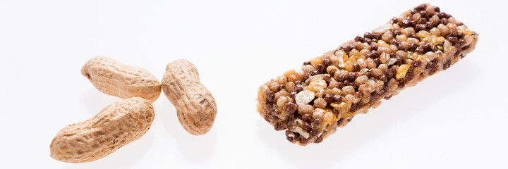 Healthy granola bar (muesli or cereal bar) and peanuts isolated on white. Panoramic image