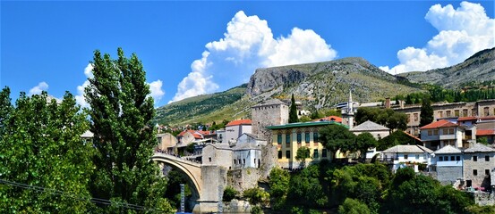 Obraz premium City of Mostar Bosnia and Hercegovina.Ancient and Ottoman City of Mostar and great Mostar Bridge. Neretva River and Vintage Buildings during sunny day and blue sky.
