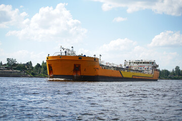 River cargo ship goes along the River on the background of blue sky with clouds