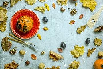 Autumn still life  flat lay. Pumpkins, plums, fallen leaves, acorns, chestnuts on a blue background, top view. Autumn harvest concept, thanksgiving day background, 
view from above