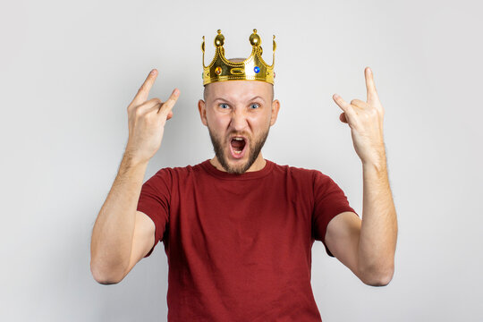 Young man in a golden crown screams and celebrates something on a light background. Concept king, luck, gain, rich, dream, goal, aspiration, bet. Banner